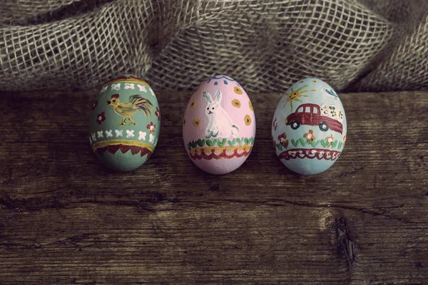 Três ovos de Páscoa em uma tábua de madeira — Fotografia de Stock