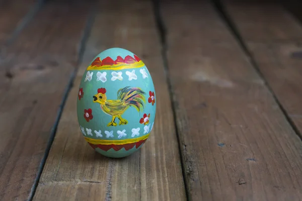 Пасхальное яйцо с петухом на деревянной доске — стоковое фото