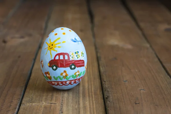 Huevo de Pascua con un coche en una tabla de madera — Foto de Stock
