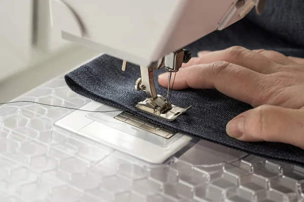 sewing machine sews denim fabric