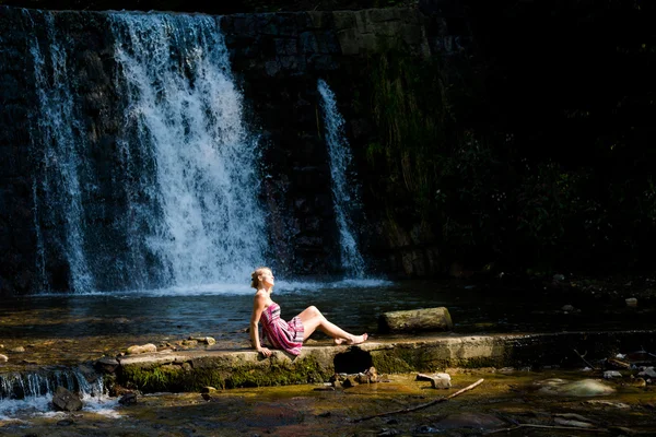 Beautiful young woman by waterfall — ストック写真