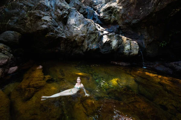 Schönes Mädchen, das im Wasserfall schwimmt — Stockfoto