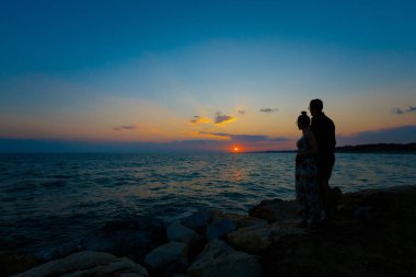 Türkiye 'nin Side kentindeki tropikal plajda altın gün batımını izleyen beyaz bir çiftle yaz manzarası. Balayı sırasında cennette çekilmiş tatil fotoğrafları..