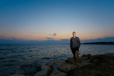 Türkiye 'nin Side kentinde tropikal plajda altın gün batımını izleyen beyaz bir genç ile yaz manzarası. Balayı sırasında cennette çekilmiş tatil fotoğrafları..