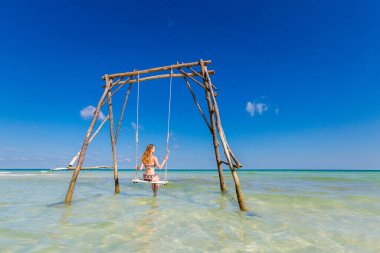 Genç seksi kadın Vietnam 'daki tropikal ada Phu Quoc' ta salıncakta. Sıcak güneşli bir günde Sao sahilinde turist.