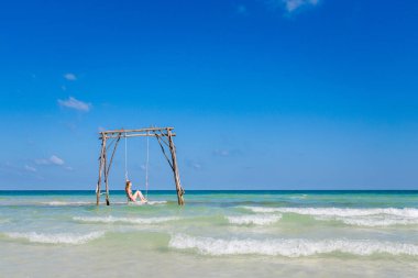 Genç seksi kadın Vietnam 'daki tropikal ada Phu Quoc' ta salıncakta. Sıcak güneşli bir günde Sao sahilinde turist.
