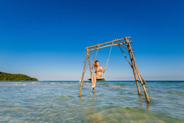Genç seksi kadın Vietnam 'daki tropikal ada Phu Quoc' ta salıncakta. Sıcak güneşli bir günde Sao sahilinde turist.