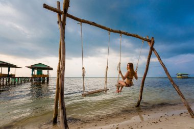 Genç seksi kadın Vietnam 'daki tropikal ada Phu Quoc' ta salıncakta. Denizyıldızı sahilinde turist, güneşli bir günde Rach Vem..