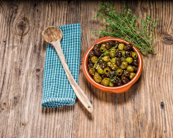 Green and black olives with wooden spoon