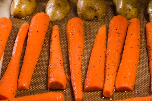 Potatoes and carrots on a baking sheet — Stock Photo, Image