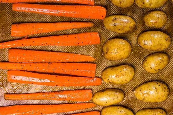 Potatoes and carrots on a baking sheet — Stock Photo, Image