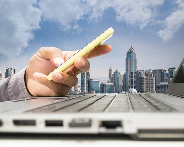 Hand close up of business man working by laptop and mobile phone with blue sky background
