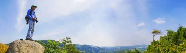A man traveler standing alone on top of mountain , Outdoor activity in Summer season at tropical forest of Thailand , Panorama view