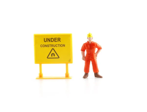 Warning sign under construction with miniature figure labo — Stock Photo, Image