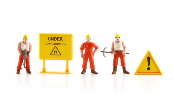 Warning sign under construction with miniature figure labo — Stock Photo, Image