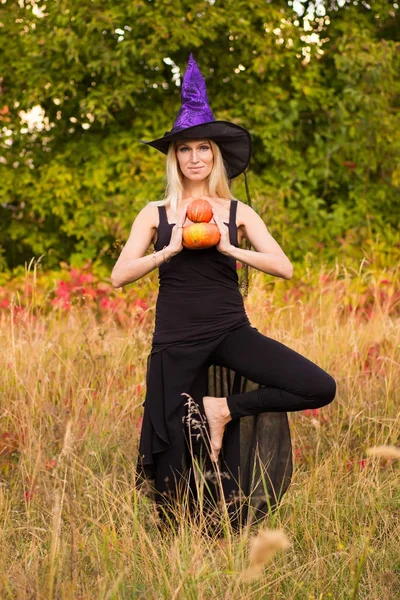 Mujer alegre en traje de bruja practicando yoga — Foto de Stock