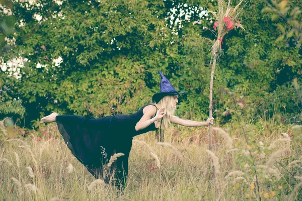 Happy girl in witch costume practicing yoga — Stock Photo, Image