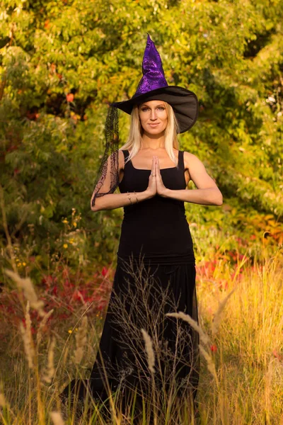 Mulher sorridente em traje de bruxa praticando ioga — Fotografia de Stock