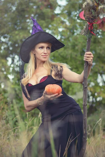 Menina jovem em traje de bruxa com vassoura — Fotografia de Stock