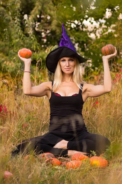 Dívka v kostýmu čarodějnice sedící v lotosu představují — Stock fotografie