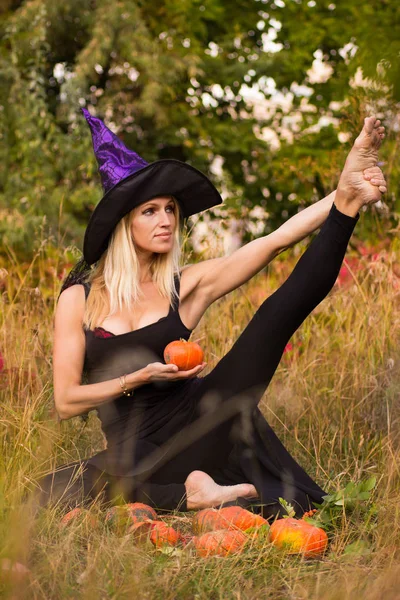 Hermosa chica en traje de bruja practicando yoga —  Fotos de Stock