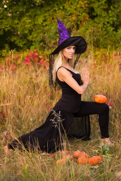 Mulher bonita em traje de bruxa praticando ioga — Fotografia de Stock