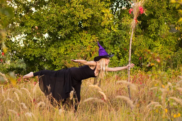 Chica rubia en traje de bruja practicando yoga —  Fotos de Stock