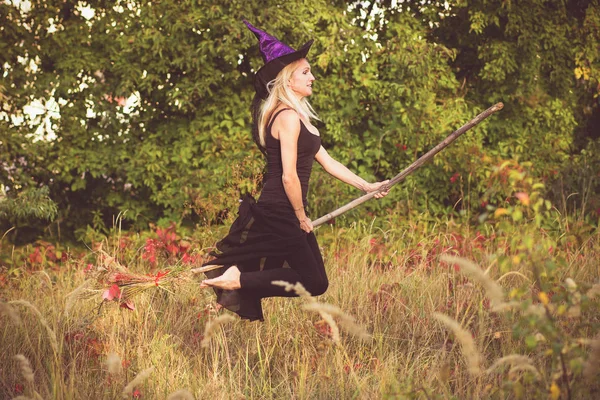 Girl in witch costume flies on broomstick — Stock Photo, Image