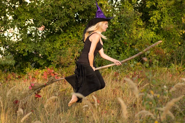 年轻的女孩在巫婆服装飞行在扫帚 — 图库照片