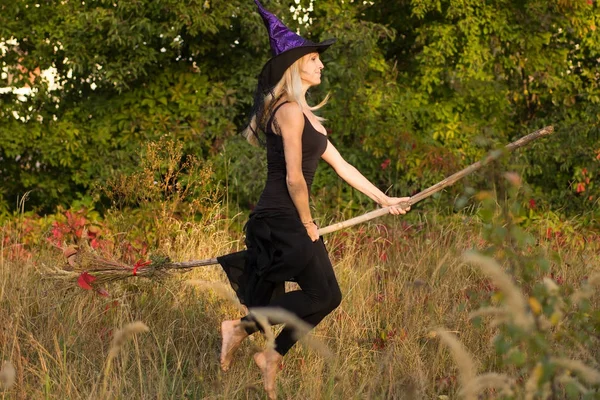 Chica adulta en traje de bruja vuela en palo de escoba —  Fotos de Stock