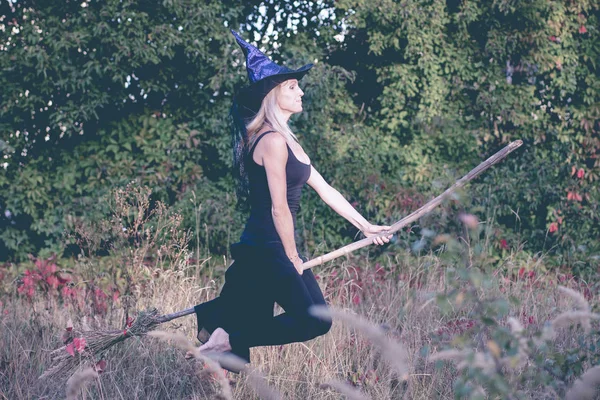 Szép lány boszorkány jelmez repül a seprű — Stock Fotó