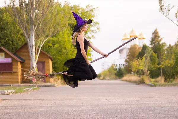 Chica feliz en traje de bruja vuela en palo de escoba —  Fotos de Stock