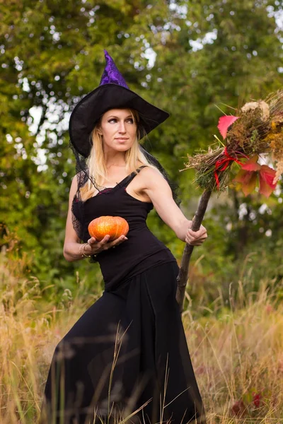 Chica sonriente en traje de bruja con palo de escoba —  Fotos de Stock