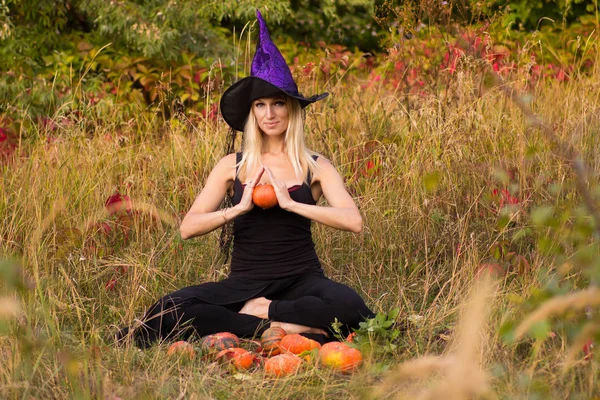 Vuxen tjej i häxa kostym utbildning lotus pose — Stockfoto