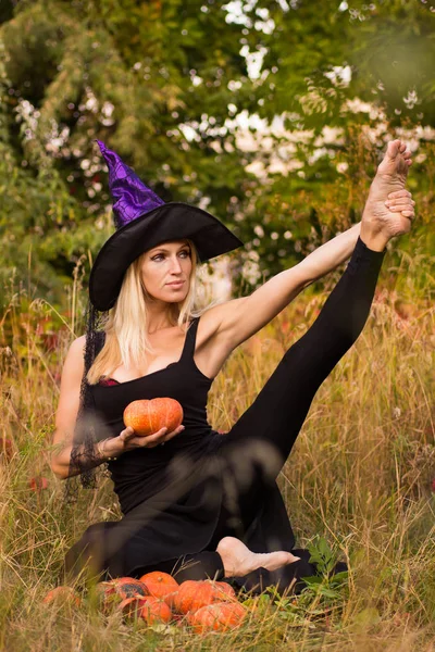 Chica alegre en traje de bruja practicando yoga —  Fotos de Stock