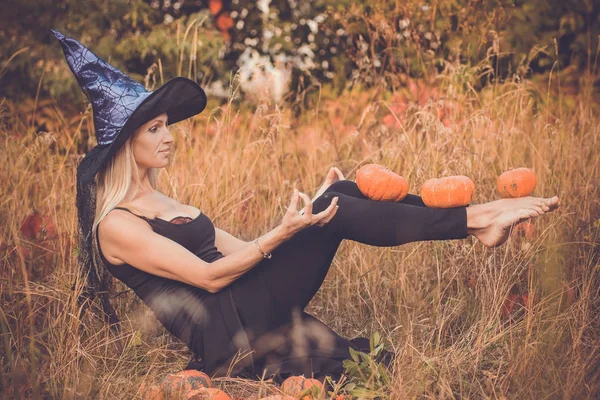 Chica riendo en traje de bruja practicando yoga — Foto de Stock