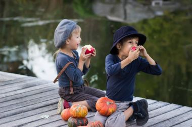 Kabak ve elma ile oturan gülümseyen çocuklar