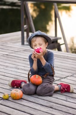 Neşeli çocuk kabak ve elma ile oturan