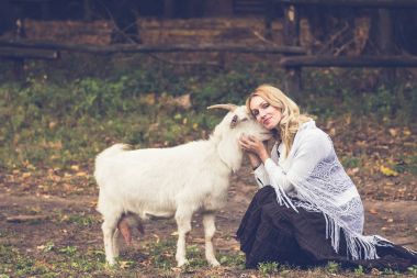 Güzel kadın keçi üzerinde yeşil bir glade okşayarak