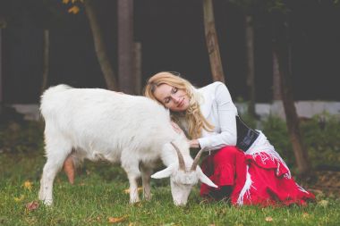 Sıradan bir kadın keçi üzerinde yeşil bir glade okşayarak