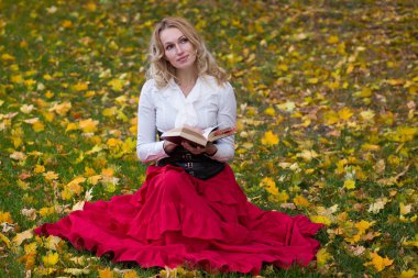Güzel kadın çimlere oturup kitap okuma