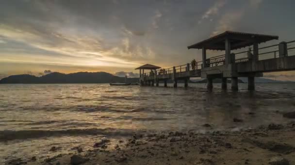 Timelapse solnedgång av en brygga med en massa sten på stranden — Stockvideo