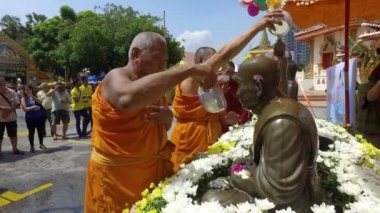 PENANG, MALAYSIA - 13 Nisan 2018: Rahipler su festivali sırasında Buda resimlerine çiçek kokulu su dökerler.
