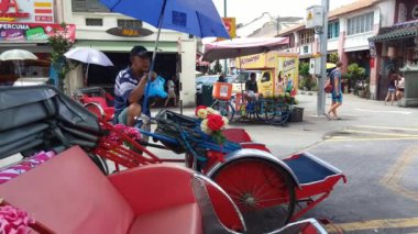 George Town, Penang / Malezya - 30 Mayıs 2018: Bir trishaw sürücüsü müşteriyi beklerken öğle yemeği yer.