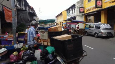 George Town, Penang / Malezya-Haziran 01-2018: Yaşlı bir adam sabah pazarında motosikletten mal taşıyor.