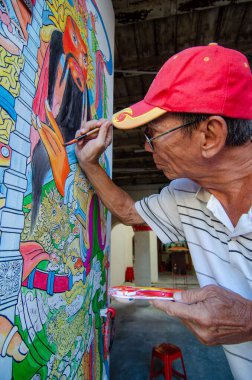 Yaşlı bir adam tapınağın kapısını boyuyor..