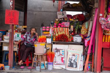 Yaşlı bir kadın, Merhamet Tanrıçası Tapınağı yakınlarındaki çöp tezgahında dinleniyor..