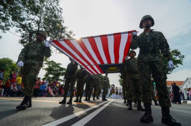 Düşük açılı askerler büyük Malezya bayrağını birlikte taşıyor.