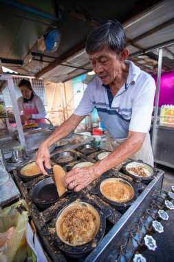 Bir adam markette Apom Balik yemeği hazırlıyor..