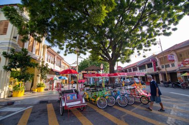 Bir adam bisikletle triportöre doğru yürüyor..